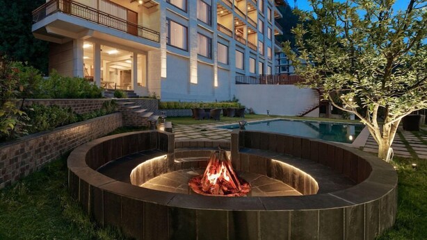 A modern hotel with a pool, outdoor seating, and a fire pit area. - Alokik Resort (Manali)