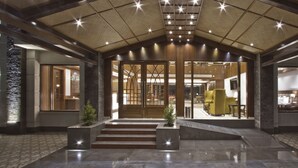 A spacious lobby with a high ceiling, a central staircase, and a reception area. - Alokik Resort (Manali)