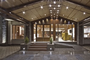 A spacious lobby with a high ceiling, a central staircase, and a reception area. - Alokik Resort (Manali)