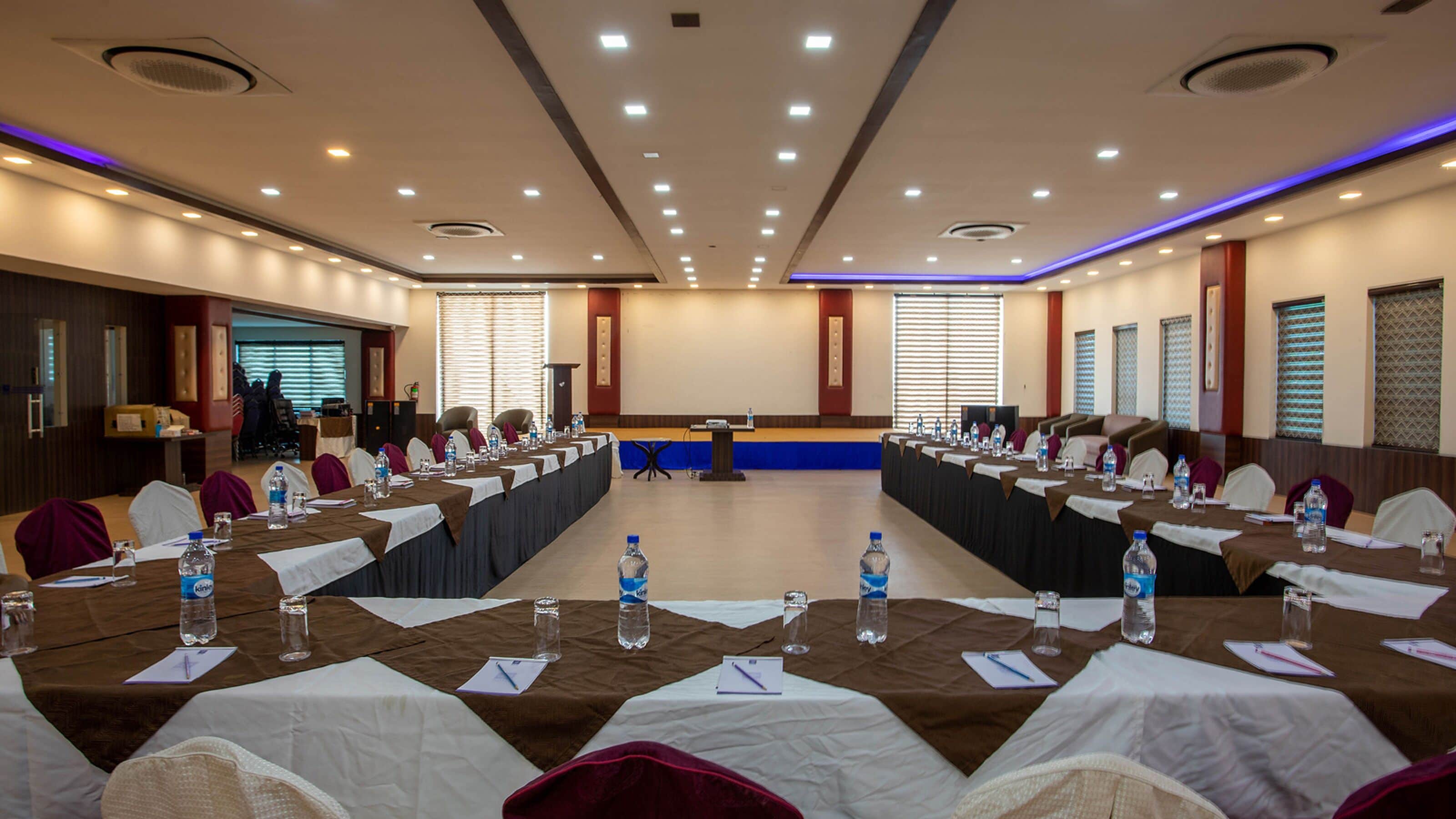 A conference room with long tables, chairs, and a podium.