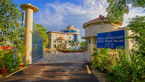 A hotel entrance with a gated driveway, a fountain, and a sign indicating the name and location of Hotel Central Plaza.