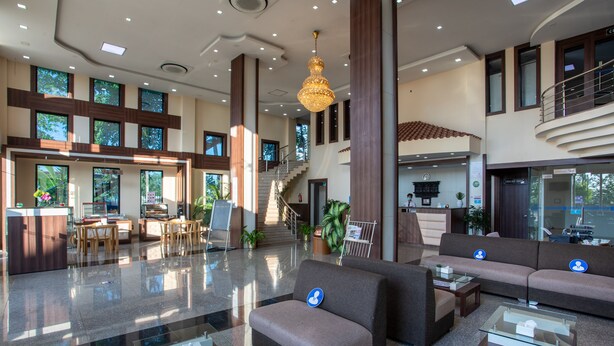 A spacious lobby with a reception desk, seating area, and a staircase leading to upper floors.