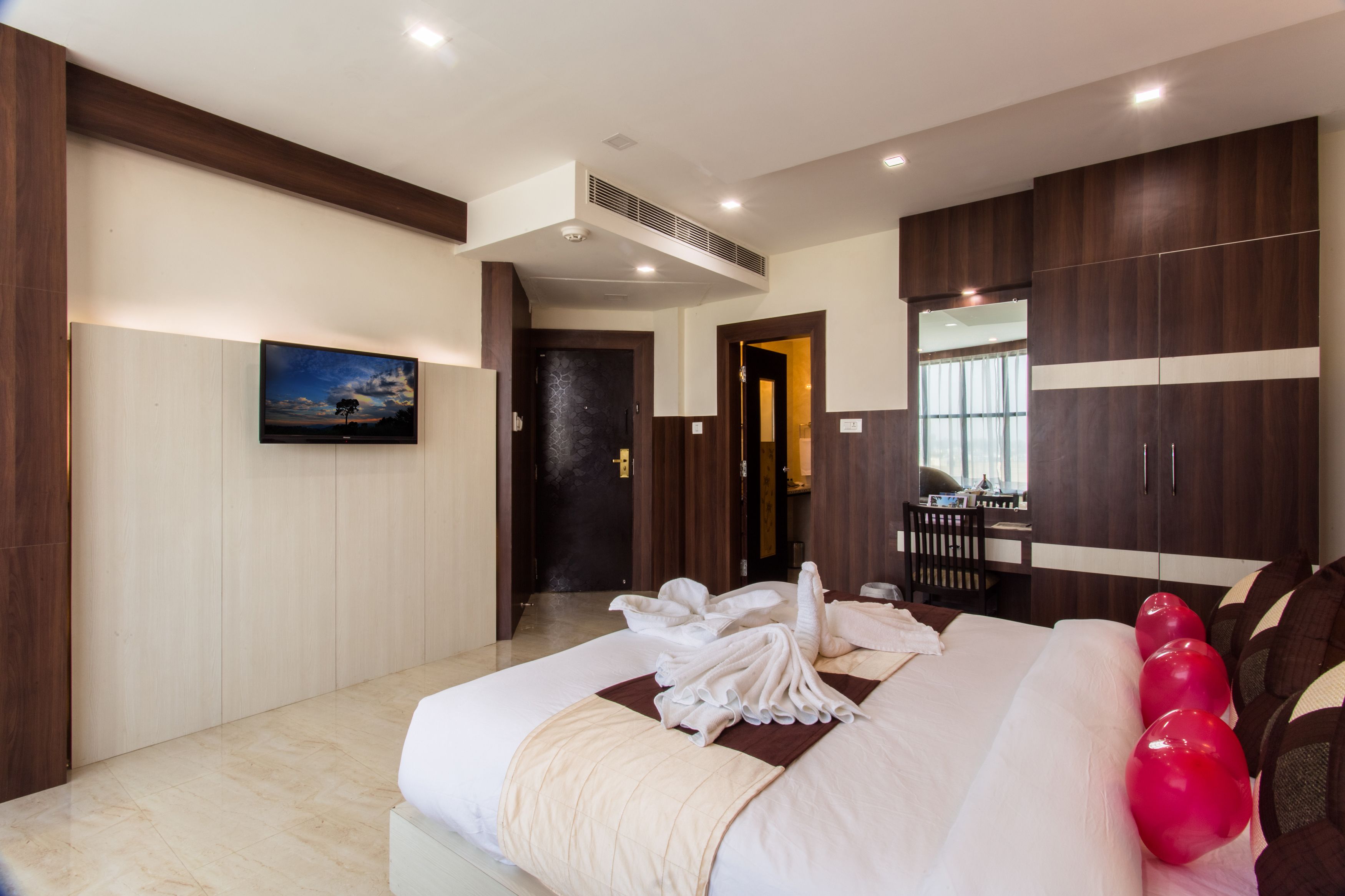 A modern hotel room with a large bed, a desk, and a wardrobe.