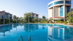 A hotel with a large pool, modern architecture, and a clear blue sky.