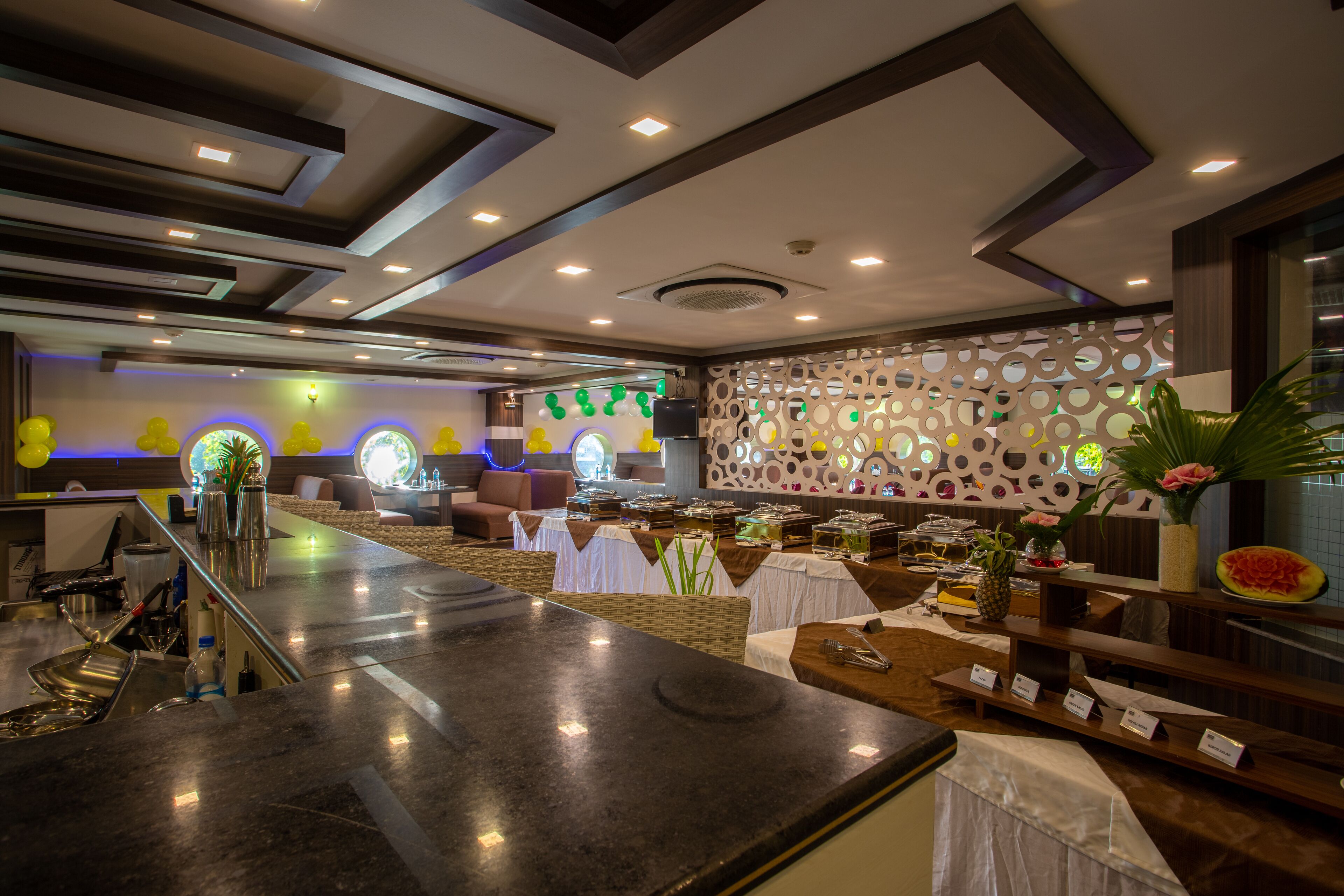 A modern hotel lobby with a reception desk, seating area, and a decorative wall with circular patterns.