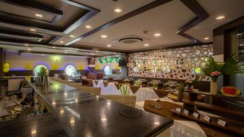 A modern hotel lobby with a reception desk, seating area, and a decorative wall with circular patterns.