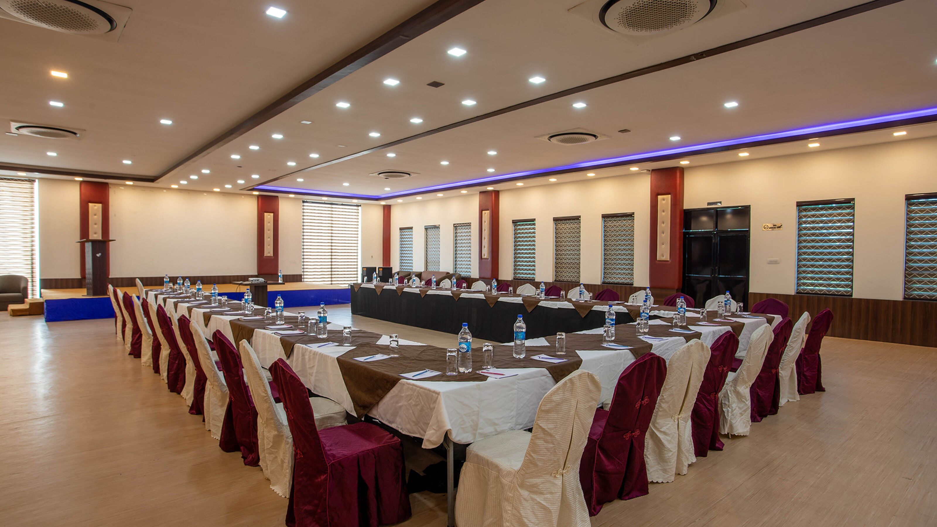 A conference room with multiple tables, chairs, and a stage.