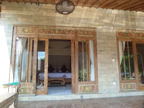 A traditional wooden structure with a bed and curtains, a woven ceiling light, and a stone wall. - Payangan Residence (Payangan)