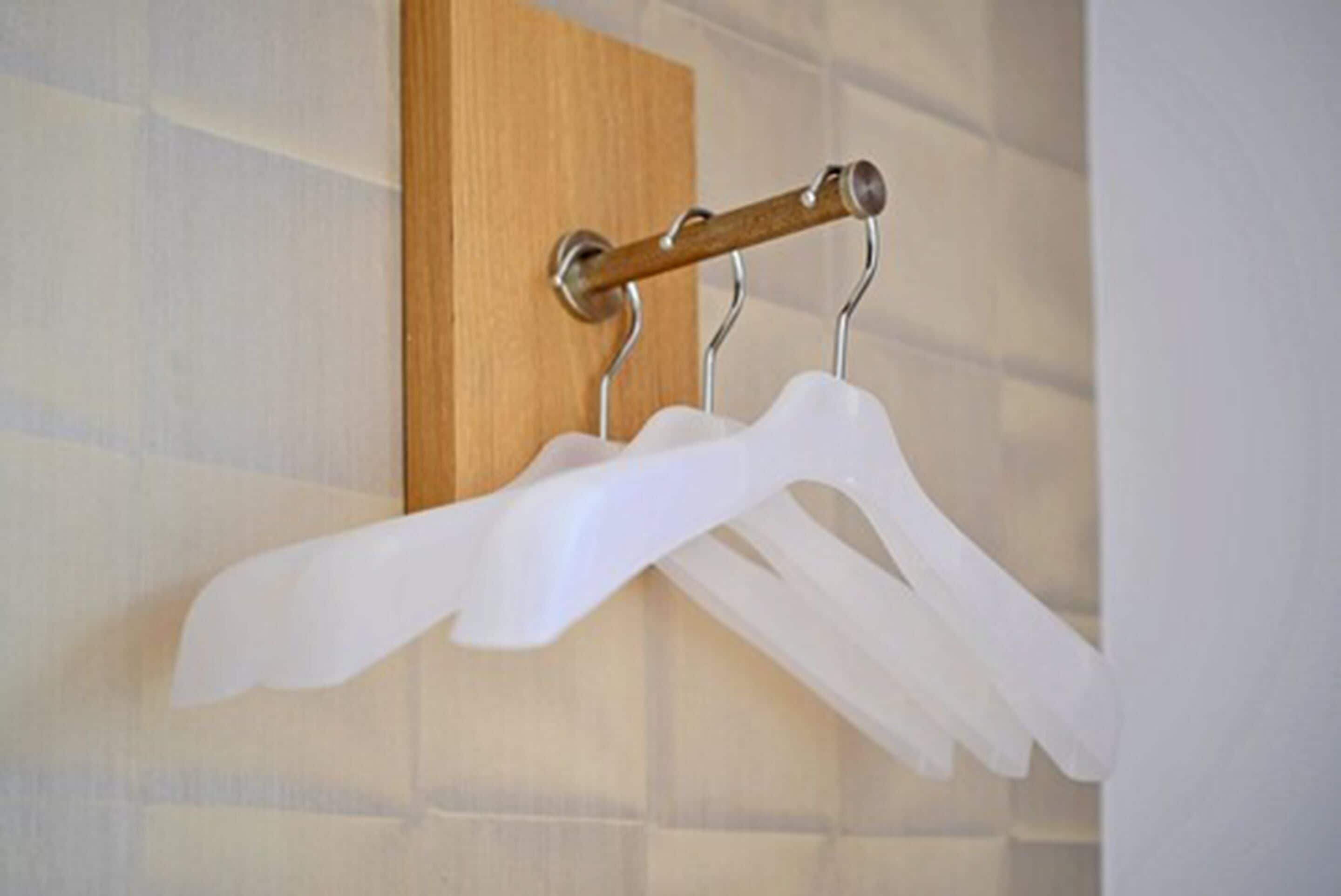Un porte-vêtements mural doté de deux cintres en plastique blanc.