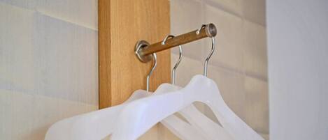 A wall-mounted rack with two white plastic hangers.