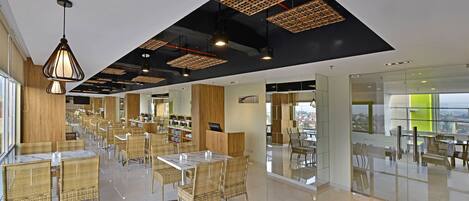 A spacious restaurant with high ceilings, modern lighting, and a view of the city.