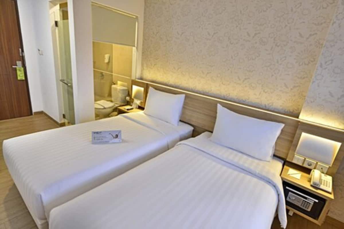 A hotel room with two beds, a bathroom, and a nightstand with a phone.