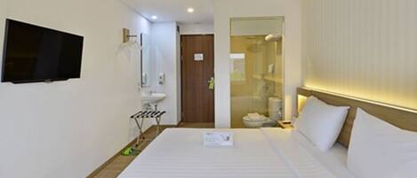 A hotel room with a bed, a television mounted on the wall, a sink, and a mirror.