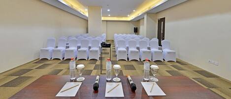 A conference room with a long table, chairs, and a speaker.