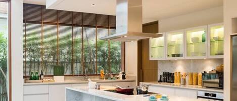 A modern kitchen with a central island, wooden stools, and built-in cabinets.