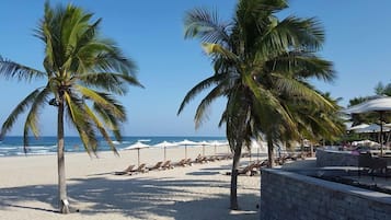 En la playa, playa de arena blanca, camastros y sombrillas 