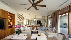 A modern living room with a sofa set, coffee tables, a TV, and a ceiling fan. - Ocean Villas Beach Resort (Da Nang)