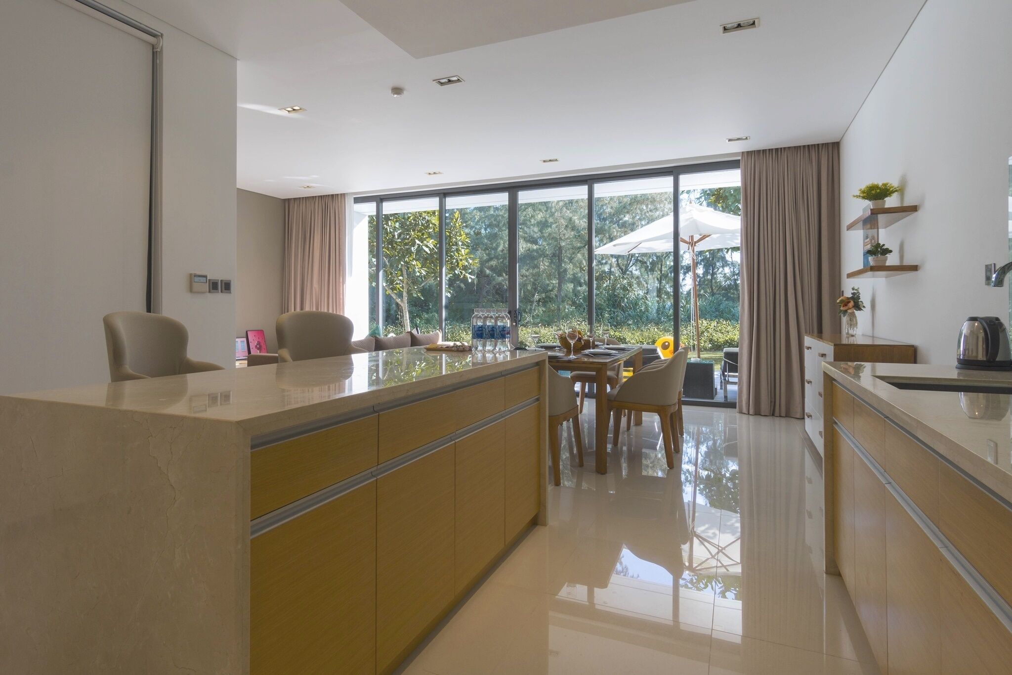 A modern kitchen with a central island, large windows, and a view of the outdoors.
