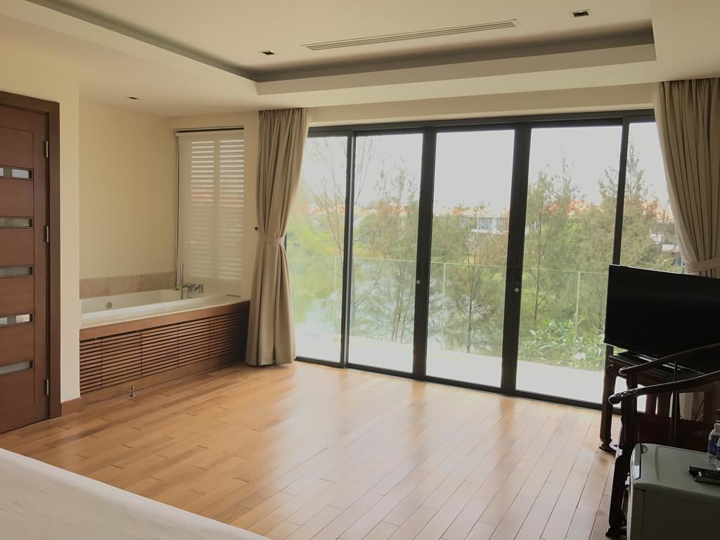 A spacious room with a large sliding glass door to a balcony, a built-in bathtub, and a flat-screen TV.