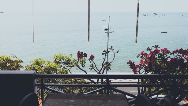A view from a balcony overlooking a calm sea with a few boats, a street lamp, and some greenery. - 86 Ha Long (Ho Chi Minh City)