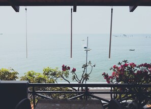 A view from a balcony overlooking a calm sea with a few boats, a street lamp, and some greenery. - 86 Ha Long (Ho Chi Minh City)