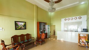 A reception area with a wooden bench, a glass cabinet, and a reception desk with a clock. - 86 Ha Long (Ho Chi Minh City)