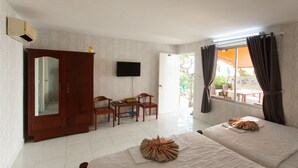 A hotel room with two beds, a wooden wardrobe, a television, a small table with chairs, and a window with curtains. - 86 Ha Long (Ho Chi Minh City)