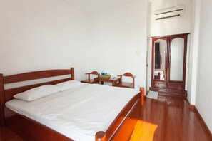 A bedroom with a wooden bed, a small wooden nightstand, a mirror, and a wardrobe. - 86 Ha Long (Ho Chi Minh City)