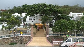 A building with a staircase leading to a balcony, surrounded by trees and a stone wall. - 86 Ha Long (Ho Chi Minh City)