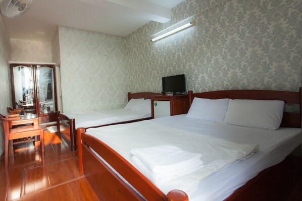 Una habitación de hotel con dos camas, un escritorio, un espejo y una televisión.