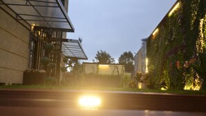 Un edificio moderno con fachada de vidrio y un jardín con plantas y flores.