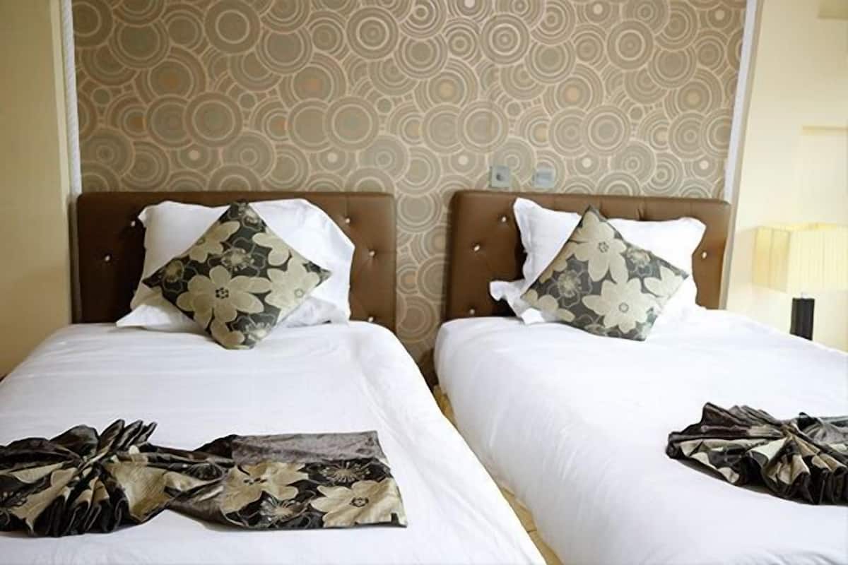 Two twin beds with floral-patterned pillows and a matching throw blanket.