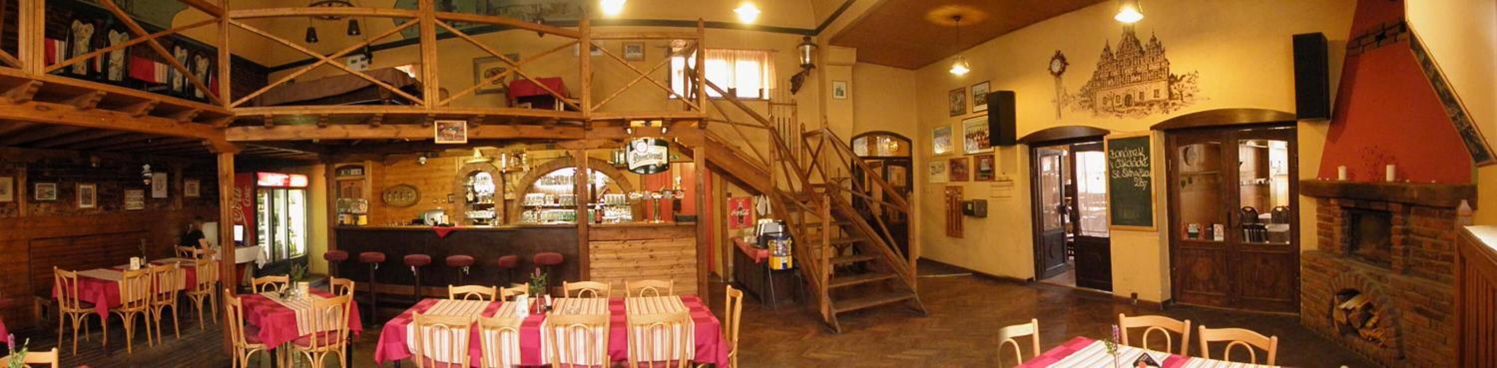 Un intérieur rustique avec des poutres en bois, un coin bar et un escalier menant à un niveau supérieur.