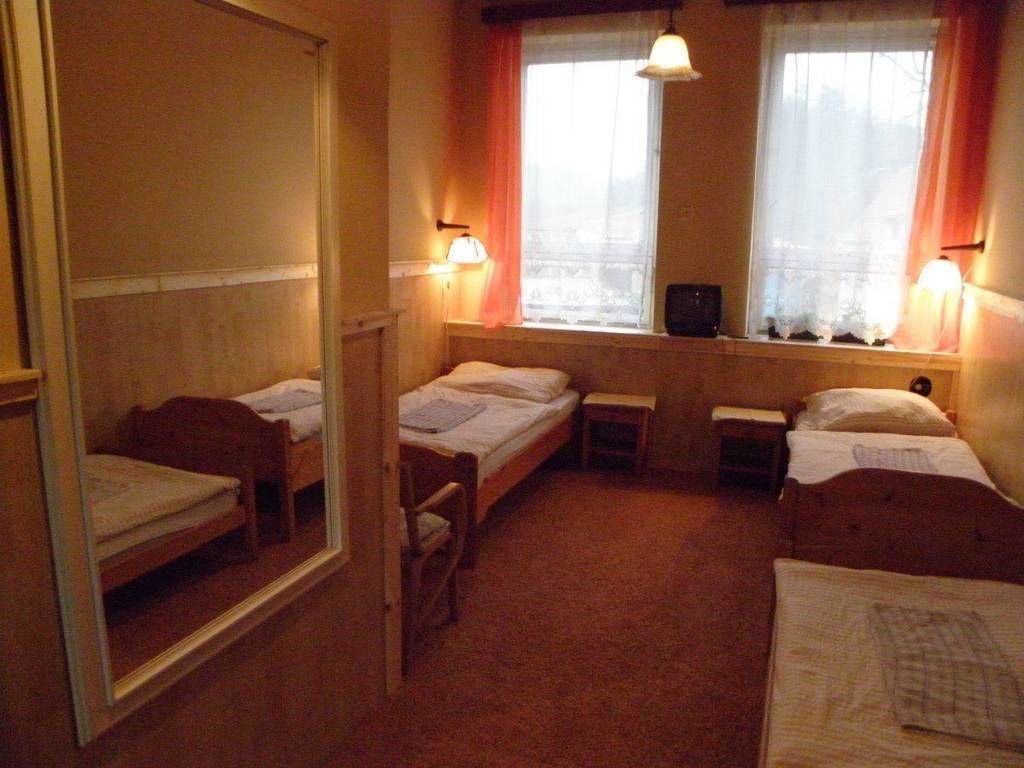 A room with three single beds, a small table, and a window with curtains.