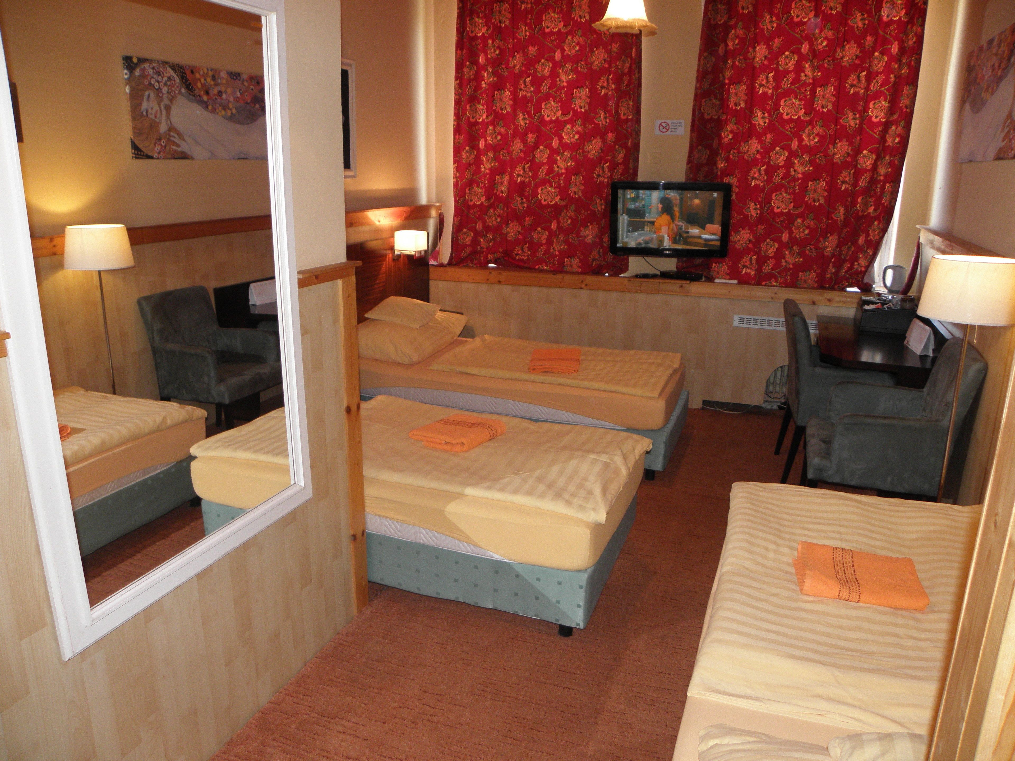 A hotel room with three beds, a television, and a desk with a chair.