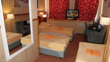 A hotel room with three beds, a television, and a desk with a chair.