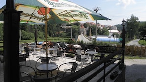 An outdoor seating area with tables and chairs, a large umbrella, and a view of a town in the background. - Hotel U Branky (Stribro)