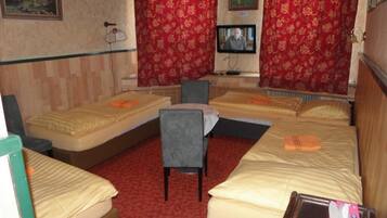 A hotel room with two beds, a chair, a television, and a red carpet.