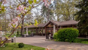 A lodge with a covered patio area, outdoor seating, and a well-maintained garden. - Puscha Congress Hotel (Kyiv)