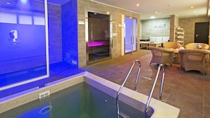 A modern indoor pool area with a glass enclosure, a lounge area with wicker furniture, and a reception desk. - Puscha Congress Hotel (Kyiv)