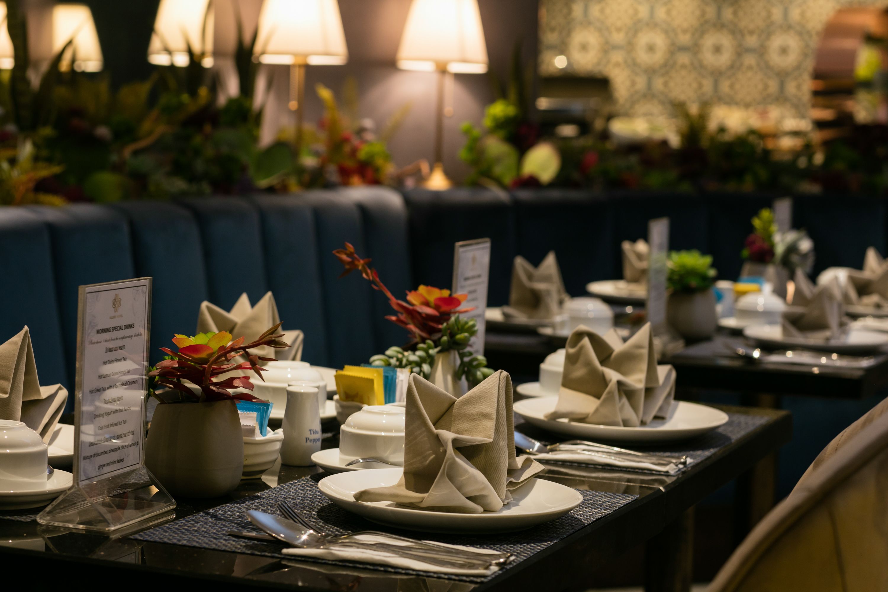 A restaurant setting with tables set for dining, including menus, plates, and napkins.