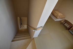 Een trap met een leuning, een wandlamp en een stapel opgevouwen dekens.