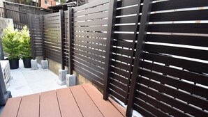 A patio area with a wooden table and a black metal fence. - ieLIFE Resort HIGASHIYAMA (Kyoto)