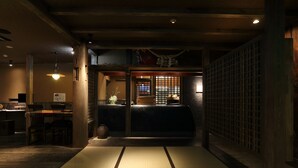A traditional Japanese room with tatami flooring, a low table with chairs, and a sliding door with a lattice design. - Shinwaen (Aso)