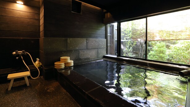 A modern bathroom with a large window, a wooden bench, and a hot tub. - Shinwaen (Aso)