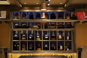 A bar area with shelves of glass jars containing various condiments and bottles.