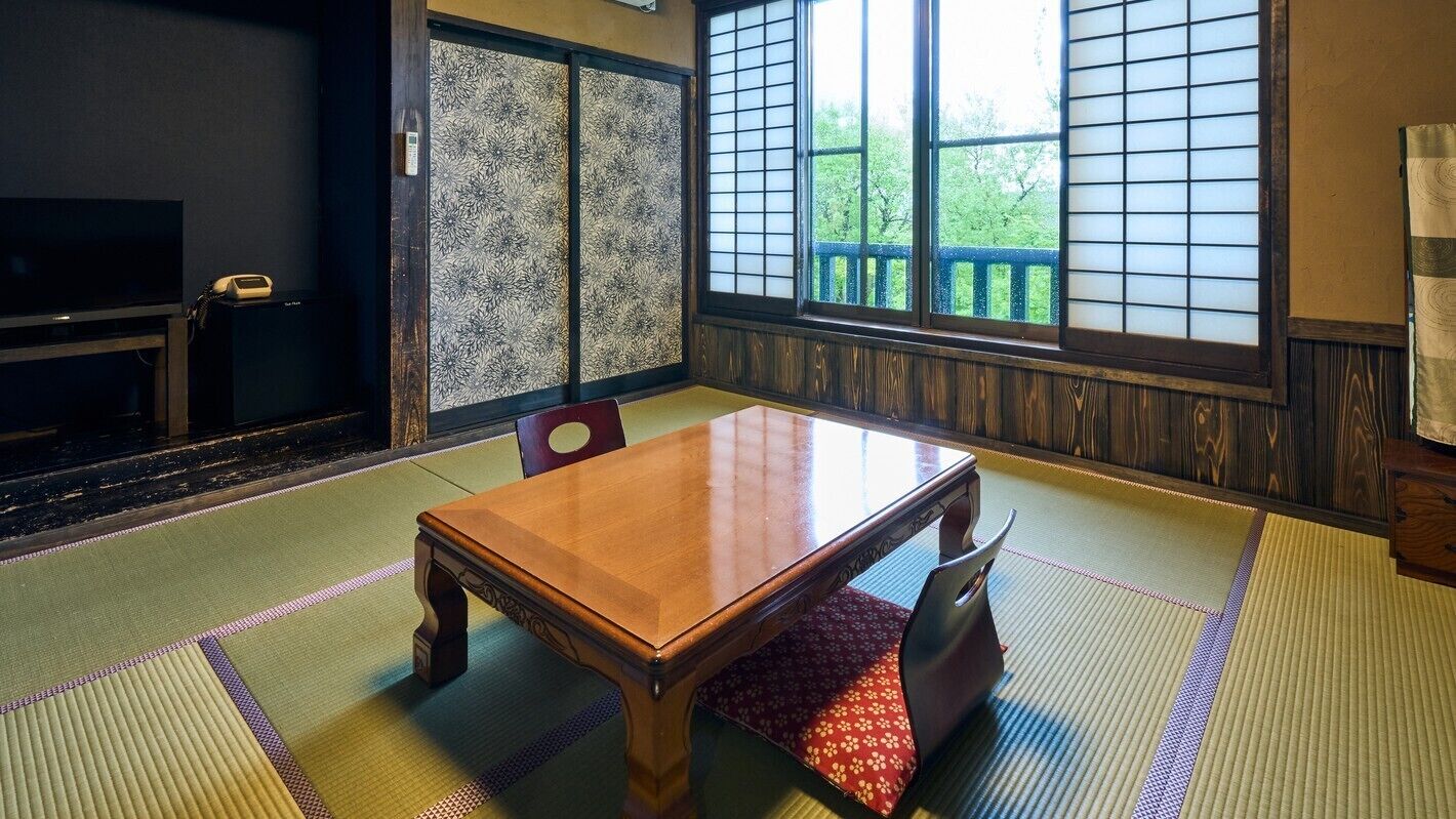 A traditional Japanese room with tatami flooring, a wooden table, and sliding doors.