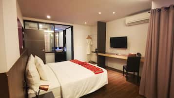 A modern hotel room with a large bed, a desk, a TV, and an air conditioning unit.