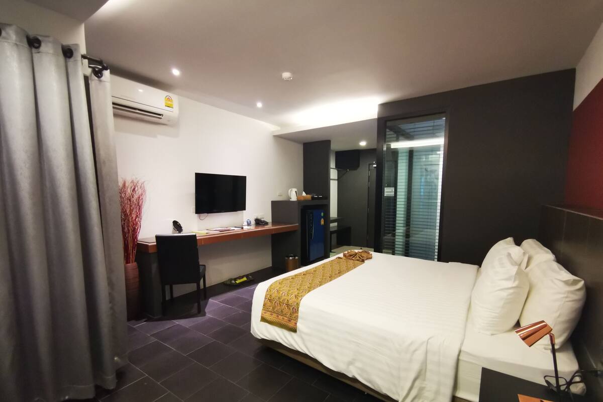Una habitación de hotel moderna con cama, escritorio y televisor.
