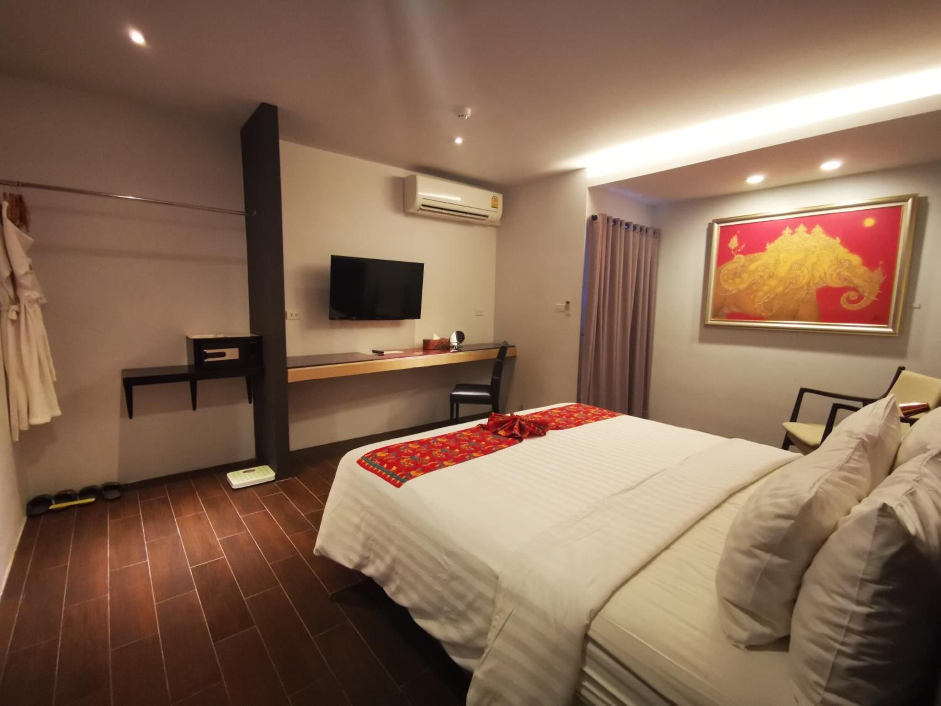 Quarto de hotel com cama, secretária, televisão e ar condicionado.